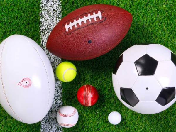 Various balls are placed on artificial grass.