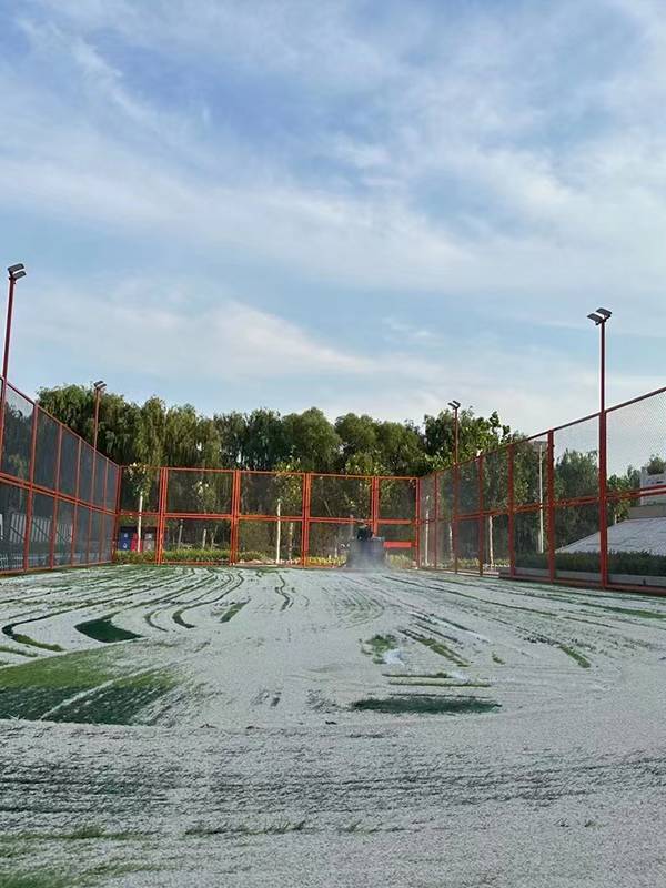 Un ouvrier nettoie le terrain de football en gazon artificiel.