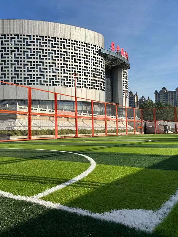 An artificial turf football field surrounded by mesh fences