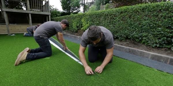 2 men are laying the artificial grass.