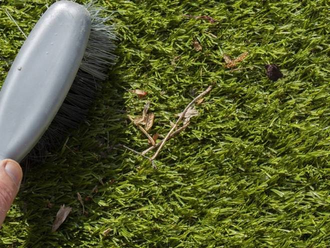 Use a brush to clean debris on the artificial grass surface.