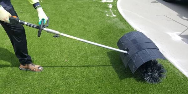 El trabajador está limpiando el césped artificial