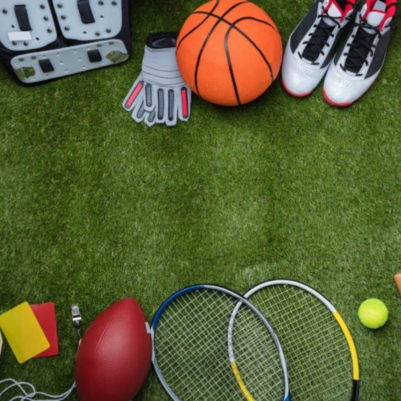 Several balls and sports equipment on the artificial grass.