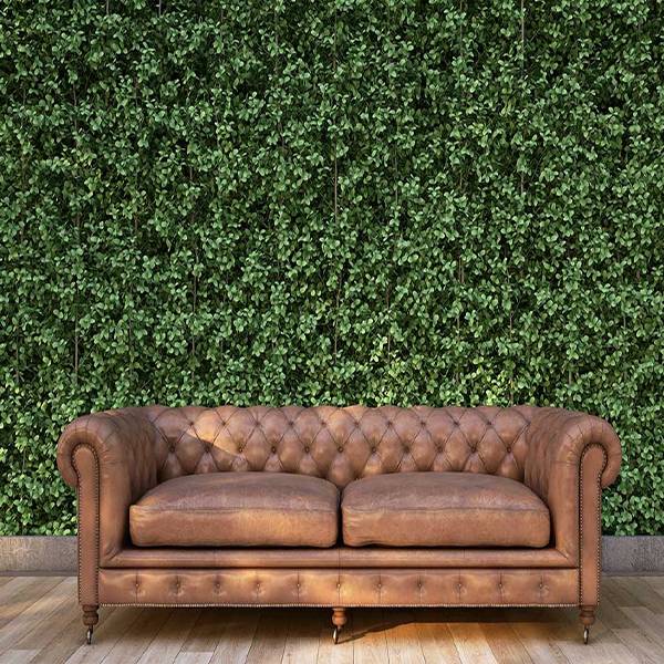 A sofa is placed against the artificial grass wall