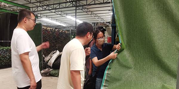 Der Abteilungsleiter stellt den Kunden aus Taiwan halbfertiges Kunstrasenmaterial vor.