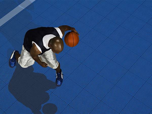 Basketball player is training on a basketball court with economical interlocking sports floor tiles.