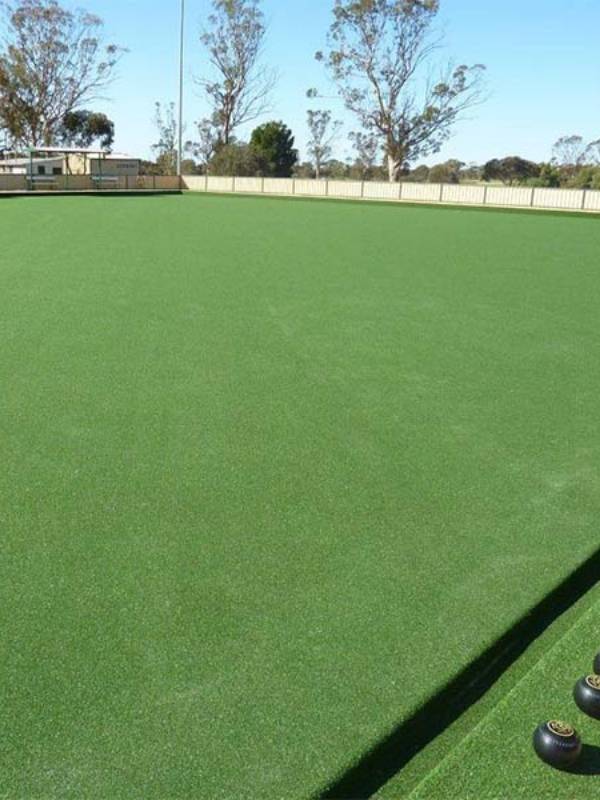Lawn bowls artificial turf with 4 lawn bowls placed on it.