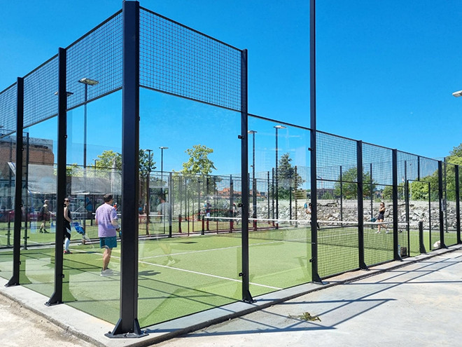 3 persons are playing in a padel court.